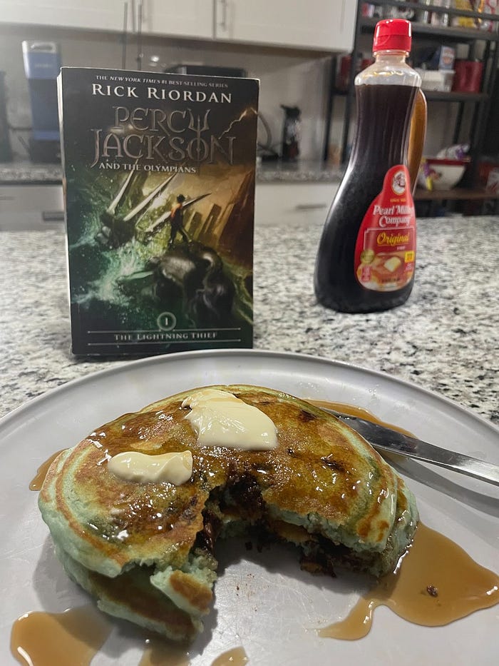 Syrup, blue pancakes, and the Percy Jackson book in the background. 